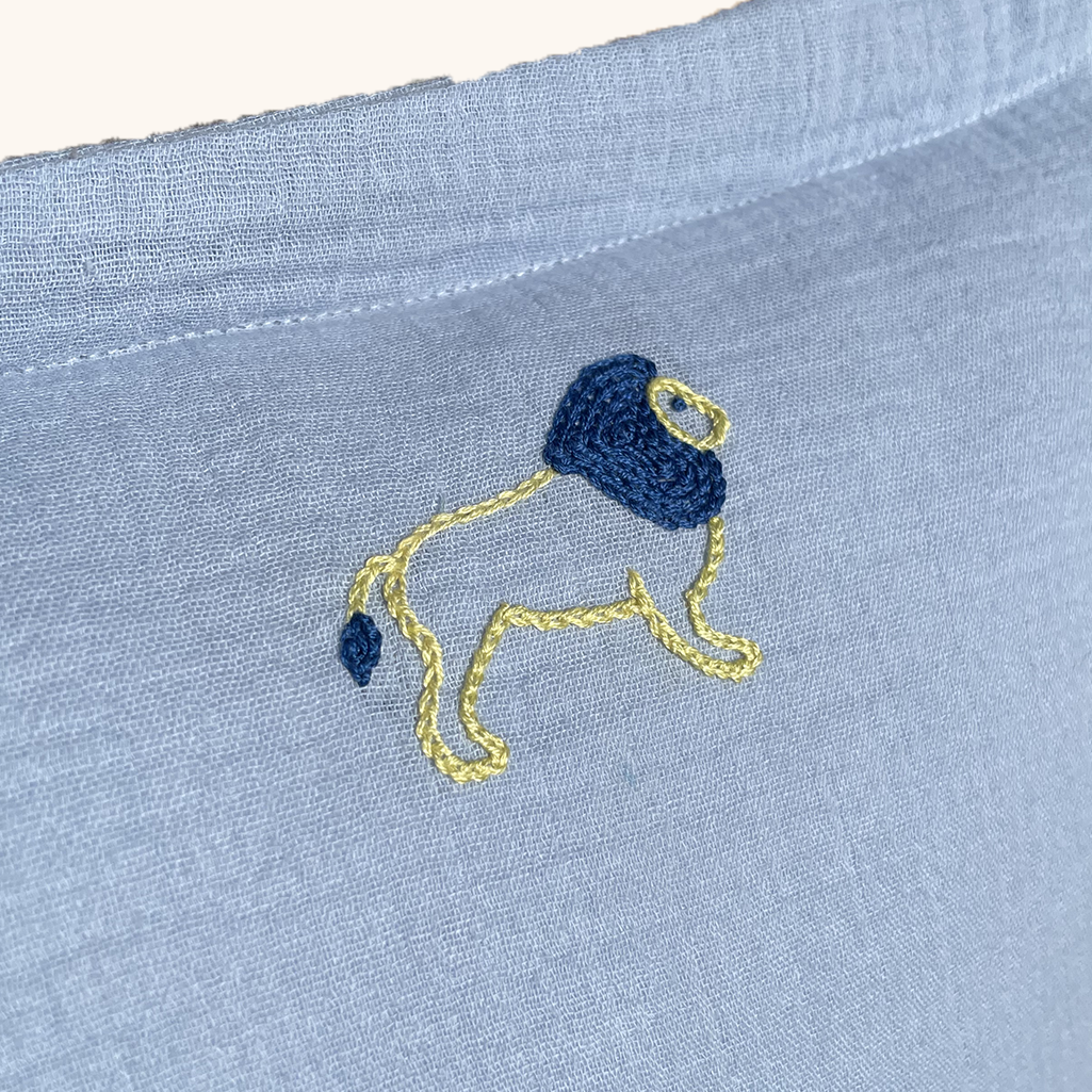 coussin gaze de coton bleu ciel zoom broderie motif lion réalisé à la main au point de chaînette. Idée cadeau de naissance décoration chambre bébé enfant