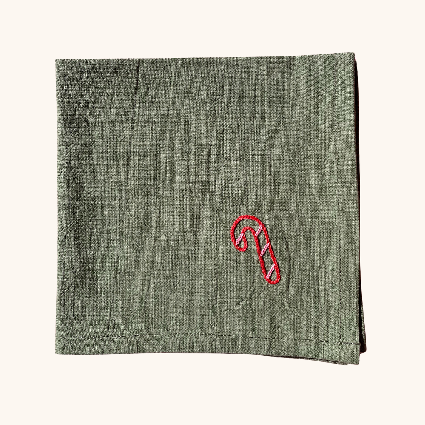 Serviette de table 35×35 cm brodée main motif sucre d'orge – linge de table artisanal et festif Savane Paris, confectionné en France, édition limitée de Noël. Couleur verte.