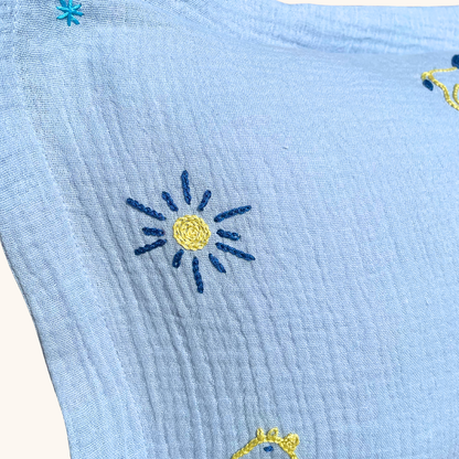 Broderie soleil artisanale au point de chaînette sur coussin de naissance bleu en gaze de coton Savane Paris
