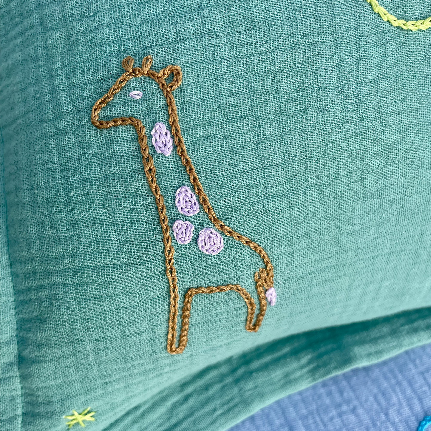 Motif girafe brodé à la main sur coussin de naissance vert Savane Paris en gaze de coton
