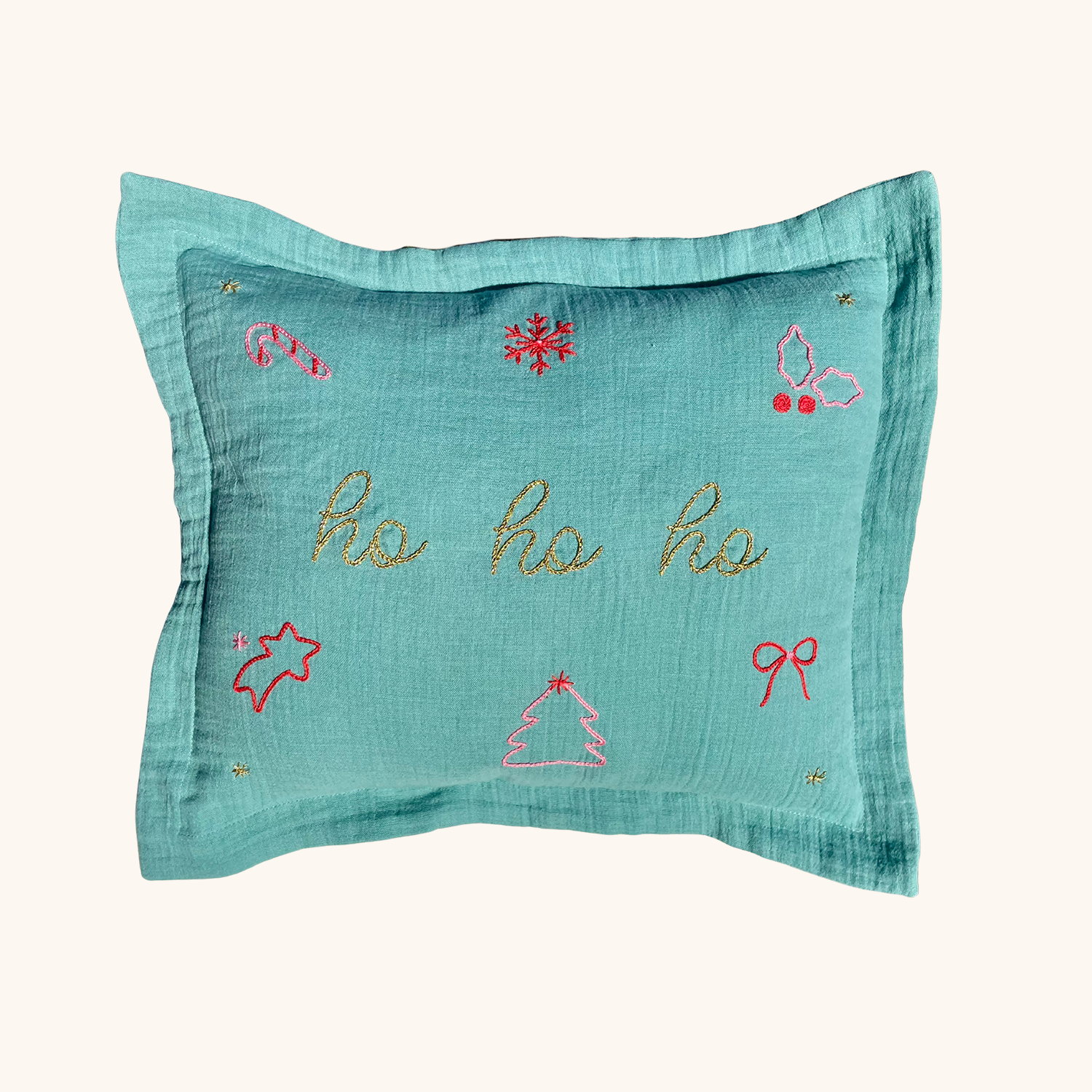Coussin de Noël vert brodé main “Ho Ho Ho” avec motifs flocon, sucre d’orge, étoile filante, houx et sapin – création artisanale en édition limitée Savane Paris.