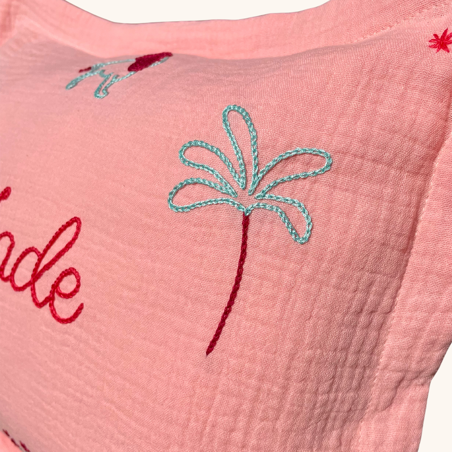 Détail de la broderie palmier sur coussin personnalisé rose Savane Paris, motif enfant brodé à la main en France.