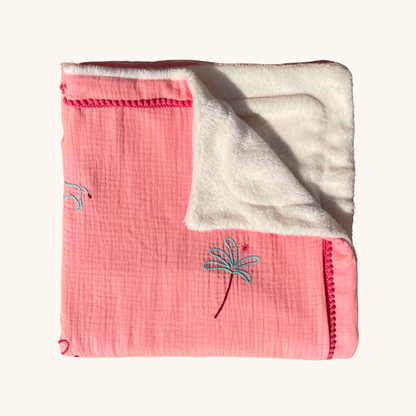 Détail d'une couverture de naissance en double gaze de coton rose, avec doublure blanche moelleuse et palmier brodé.