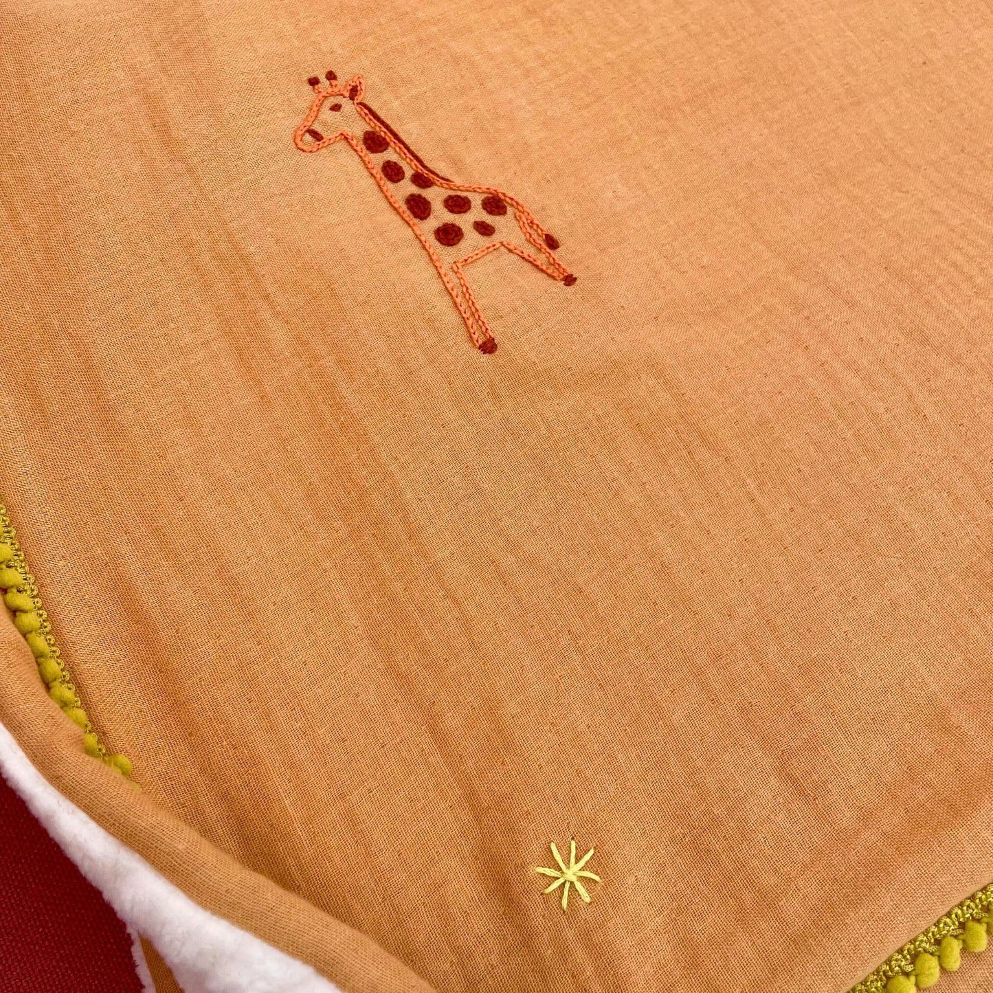 Détail broderie girafe sur plaid bébé Savane, couverture de naissance brodée à la main au point de chaînette.
