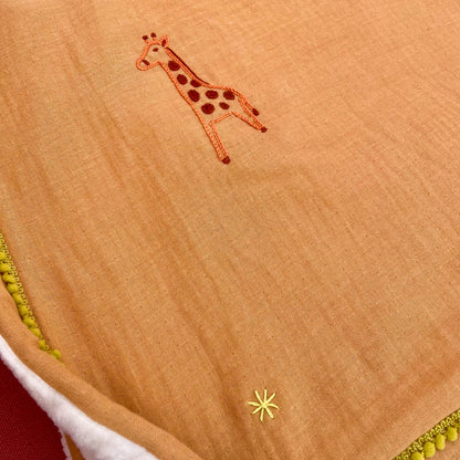 Détail broderie girafe sur plaid bébé Savane, couverture de naissance brodée à la main au point de chaînette.