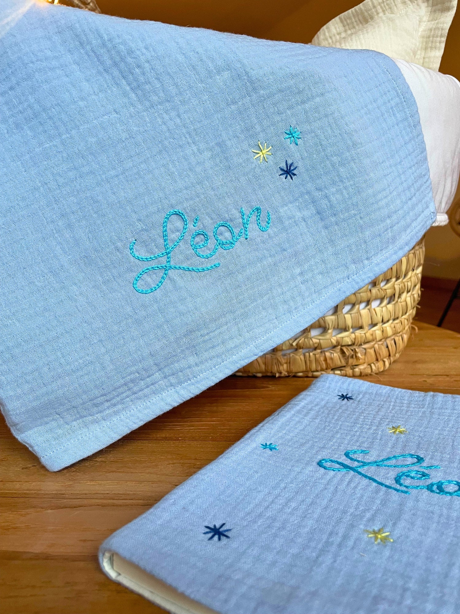 Lange bébé bleu personnalisé au prénom et carnet de santé assorti, brodés à la main, présentés comme un coffret de naissance.