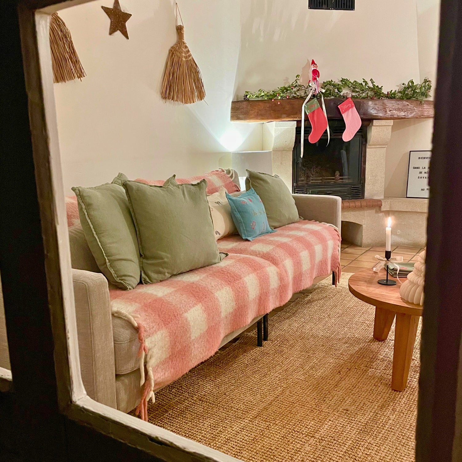 Vue depuis l’extérieur de la Maison de Noël Savane Paris, laissant apparaître un canapé décoré et une ambiance chaleureuse de Noël. Au Domaine de la Bastidonne à Céreste-en-Luberon. 