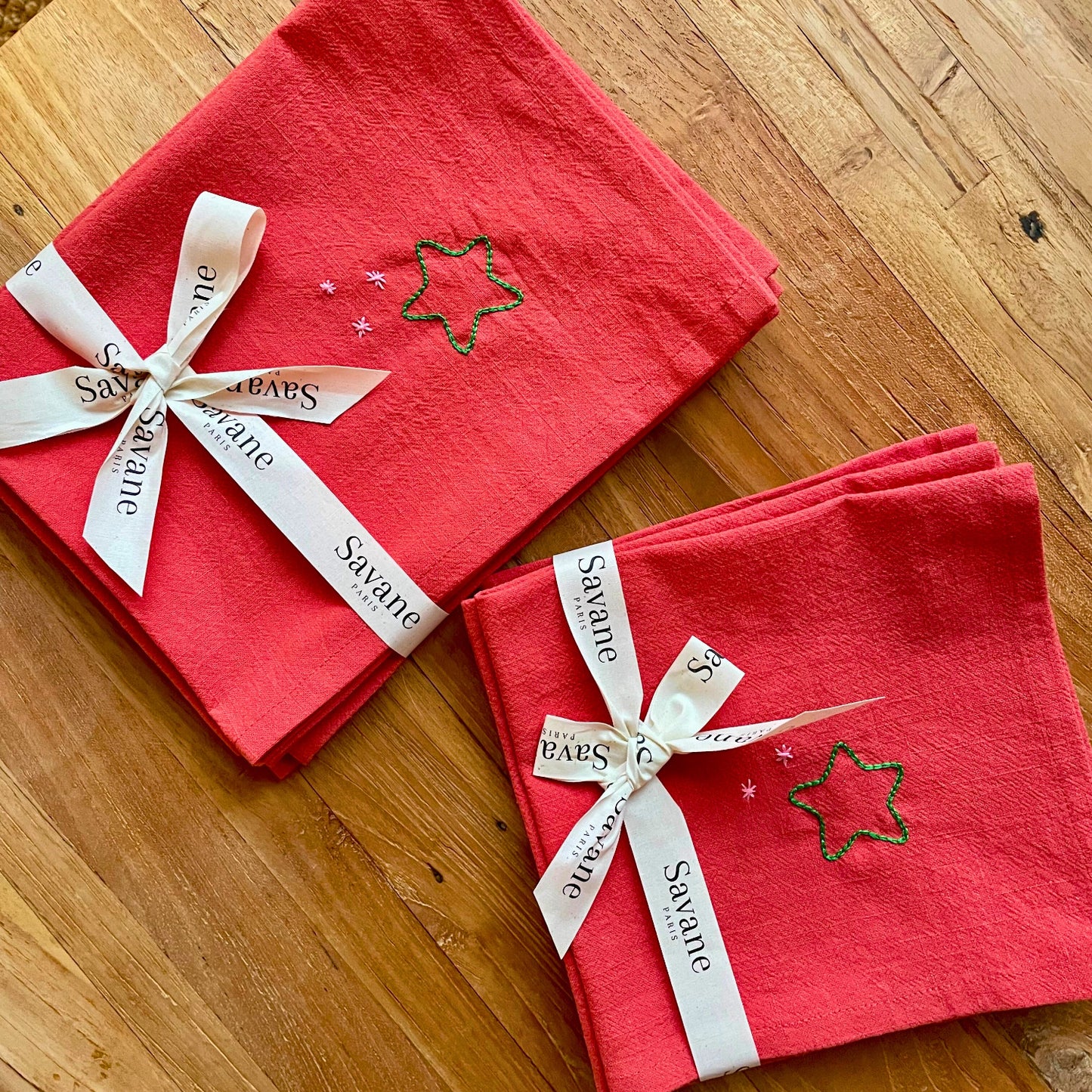 Set et serviettes de table de Noël rouges brodés motif étoiles, présentés en lot et emballés avec un ruban cadeau Savane