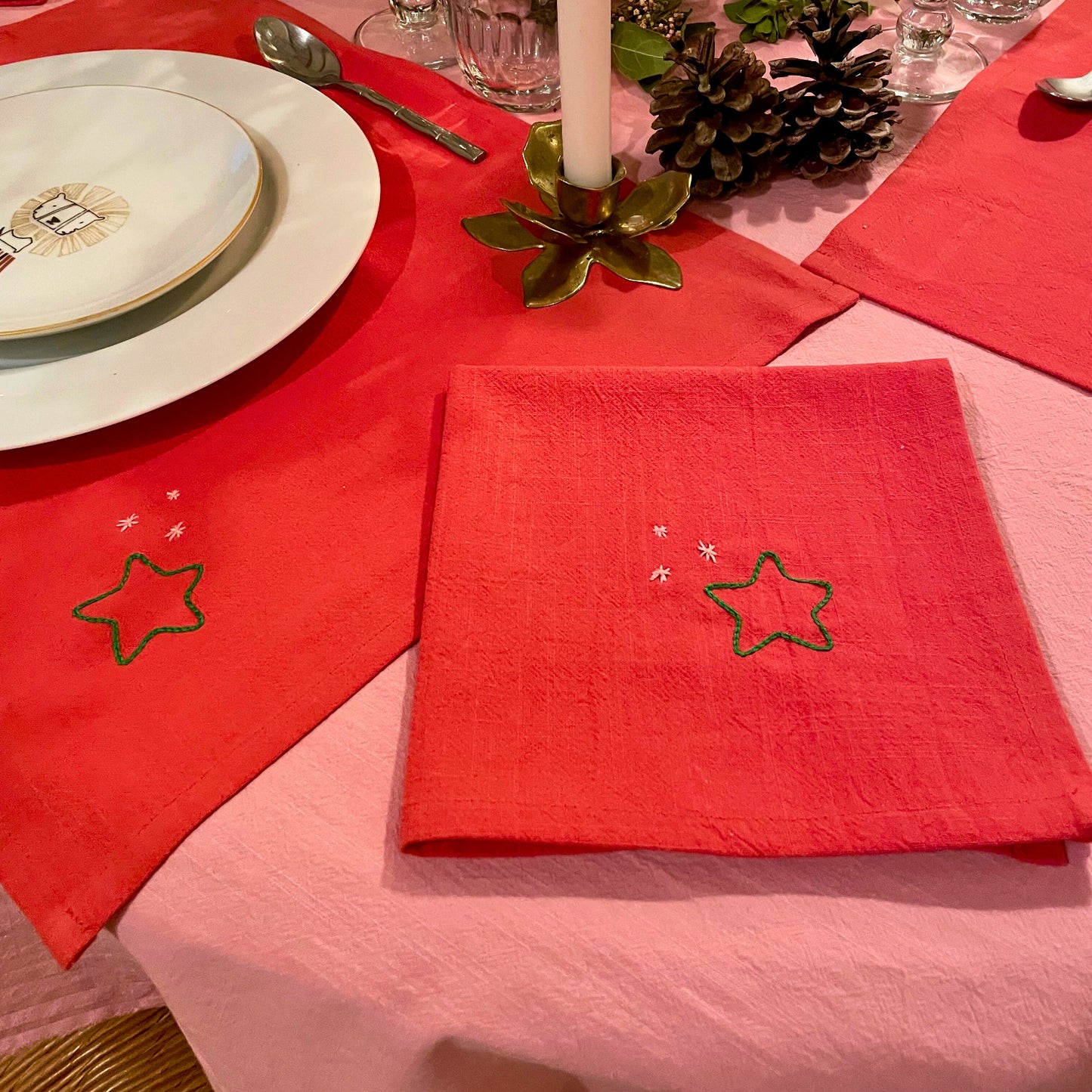 Détail des sets et serviettes de table de Noël rouges Savane Paris, broderie étoiles faite main, art de la table raffiné pour les fêtes.