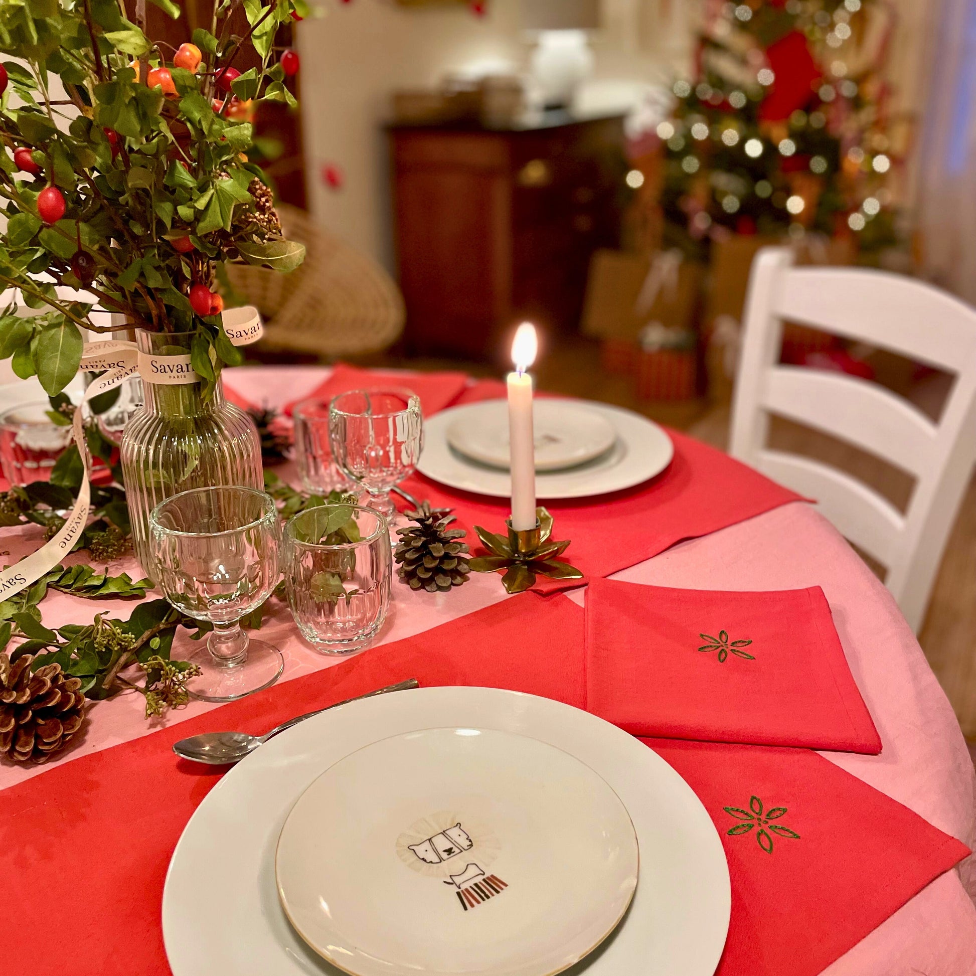 Table de Noël Savane Paris dressée avec sets et serviettes de table rouges brodés à la main, motif feuillage d'hiver, étoiles, houx, noeud, décoration de fête élégante et artisanale made in France.
