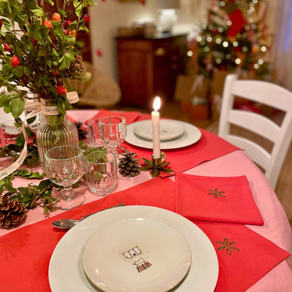 Table de Noël Savane Paris dressée avec sets et serviettes de table rouges brodés à la main, motif feuillage d'hiver, étoiles, houx, noeud, décoration de fête élégante et artisanale made in France.