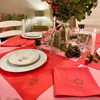 Table de Noël Savane Paris dressée avec sets et serviettes rouges brodés, ambiance chaleureuse dans la maison de Noël, décoration artisanale made in France.