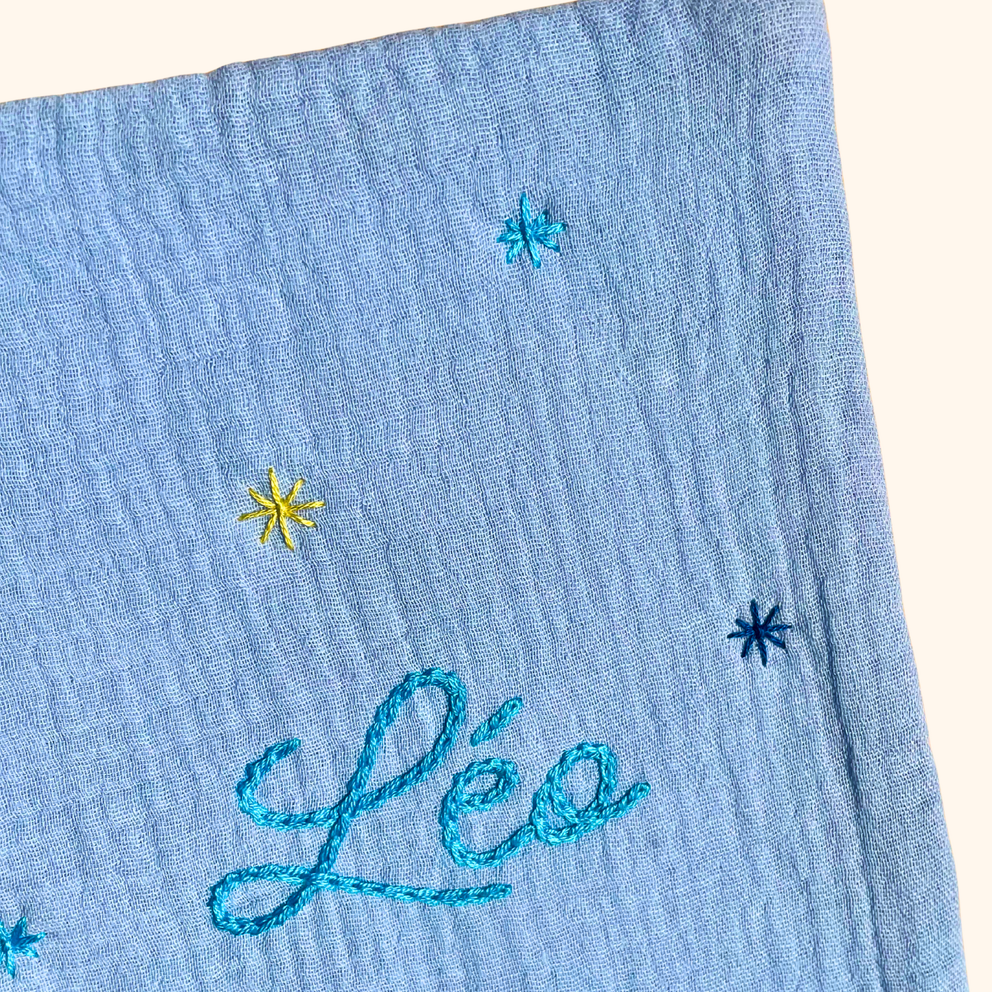 Gros plan sur les étoiles brodées à la main sur un protège carnet de santé bleu ciel personnalisé – création artisanale Savane Paris fabriquée en France.