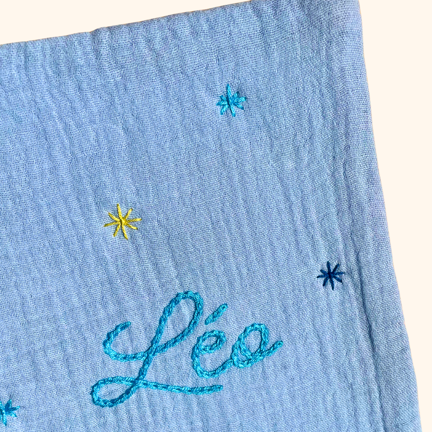 Gros plan sur les étoiles brodées à la main sur un protège carnet de santé bleu ciel personnalisé – création artisanale Savane Paris fabriquée en France.