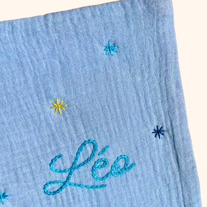 Gros plan sur les étoiles brodées à la main sur un protège carnet de santé bleu ciel personnalisé – création artisanale Savane Paris fabriquée en France.