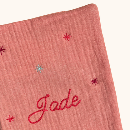 Gros plan sur les étoiles brodées à la main sur un protège carnet de santé rose personnalisé – création artisanale Savane Paris fabriquée en France.