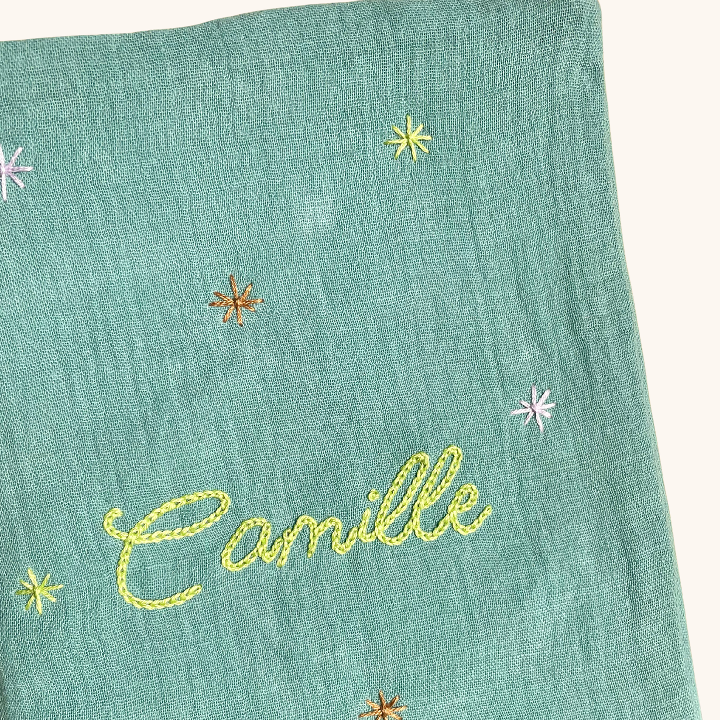Gros plan sur les étoiles brodées à la main sur un protège carnet de santé vert personnalisé – création artisanale Savane Paris fabriquée en France.