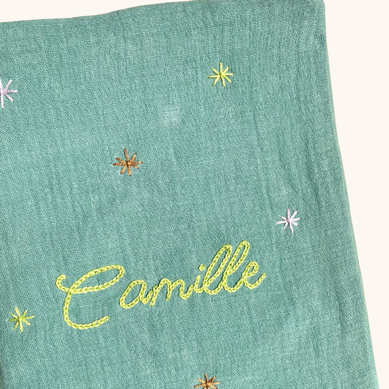 Gros plan sur les étoiles brodées à la main sur un protège carnet de santé vert personnalisé – création artisanale Savane Paris fabriquée en France.