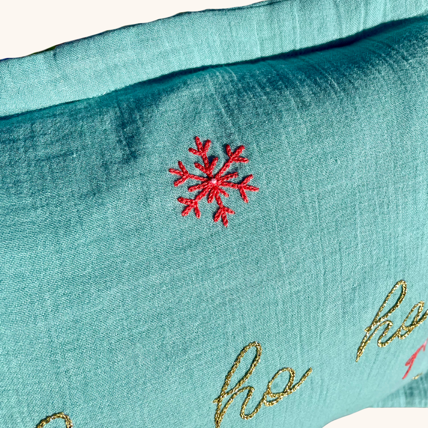 Gros plan sur flocon rouge brodé à la main sur coussin de Noël vert “Ho Ho Ho”, création artisanale Savane Paris en gaze de coton – édition limitée.
