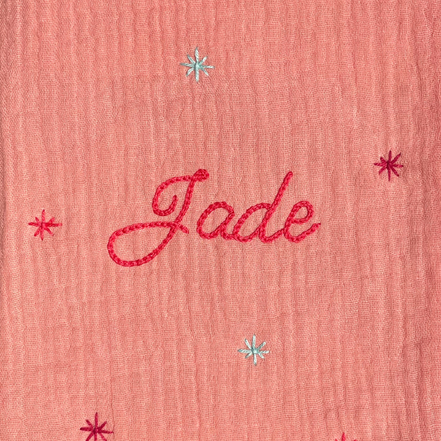 Zoom sur la broderie du prénom réalisée à la main sur un protège carnet de santé rose Savane Paris – fil DMC, savoir-faire artisanal français, cadeau de naissance personnalisé.