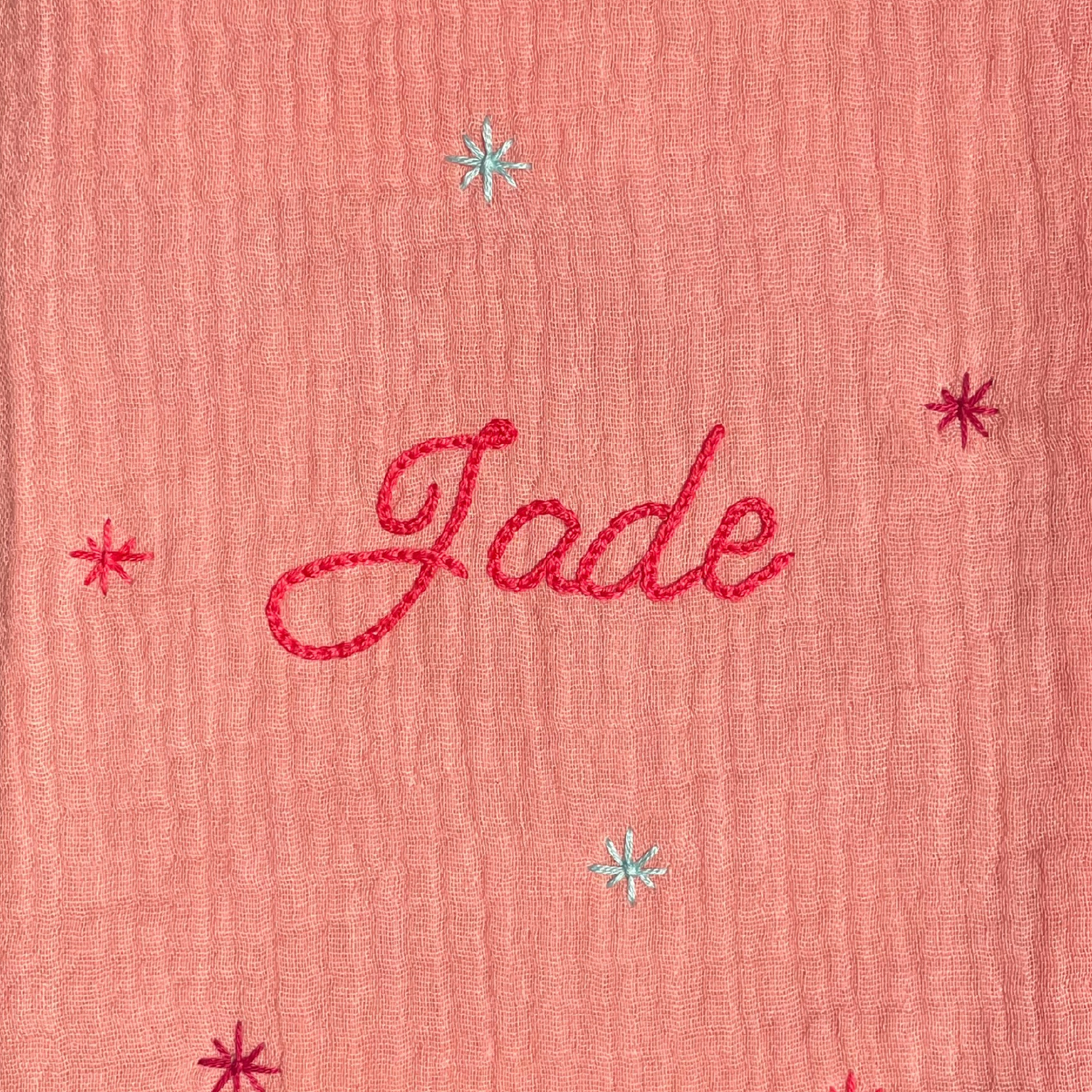 Zoom sur la broderie du prénom réalisée à la main sur un protège carnet de santé rose Savane Paris – fil DMC, savoir-faire artisanal français, cadeau de naissance personnalisé.