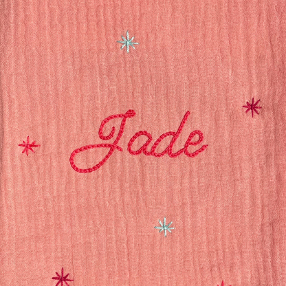 Zoom sur la broderie du prénom réalisée à la main sur un protège carnet de santé rose Savane Paris – fil DMC, savoir-faire artisanal français, cadeau de naissance personnalisé.